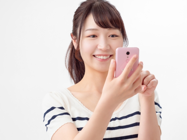 笑顔でスマホを見つめる女性