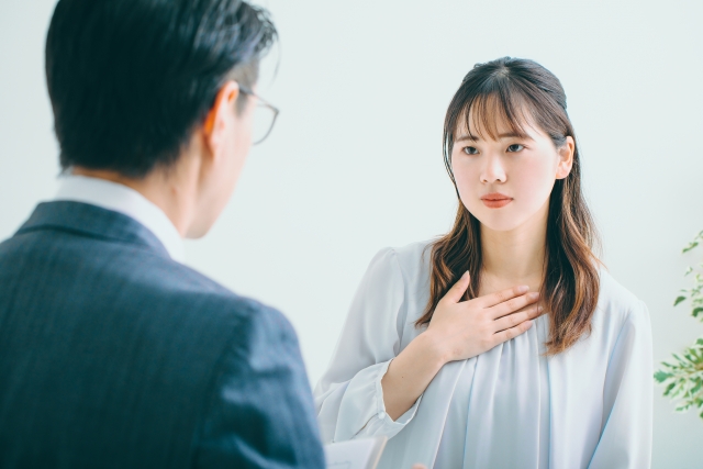 胸に手を当て緊張する女性