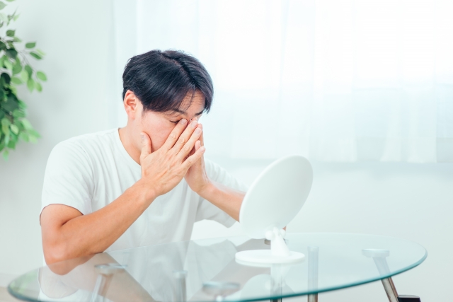 鏡を見て気にする男性