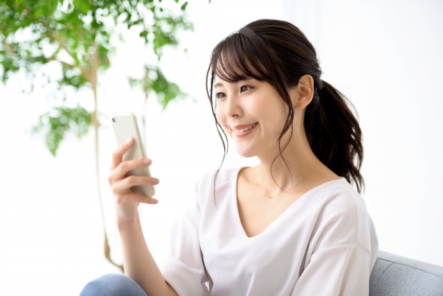 笑顔でスマホを見つめる女性