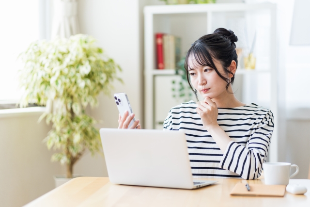 パソコンとスマホを見る女性